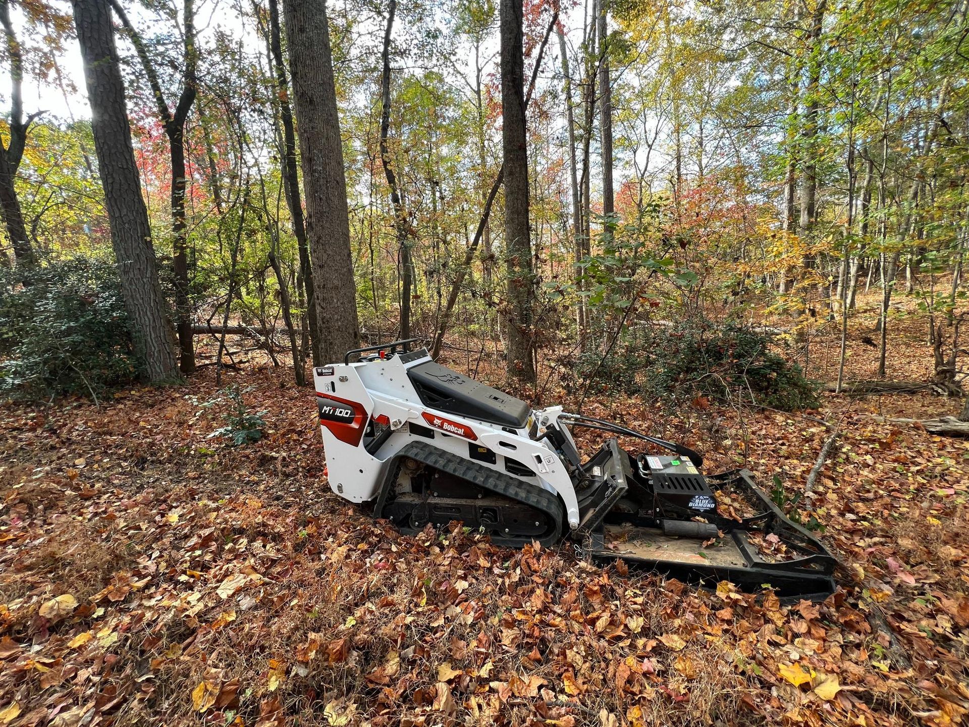 A bulldozer is sitting on top of a pile of leaves in the middle of a forest.