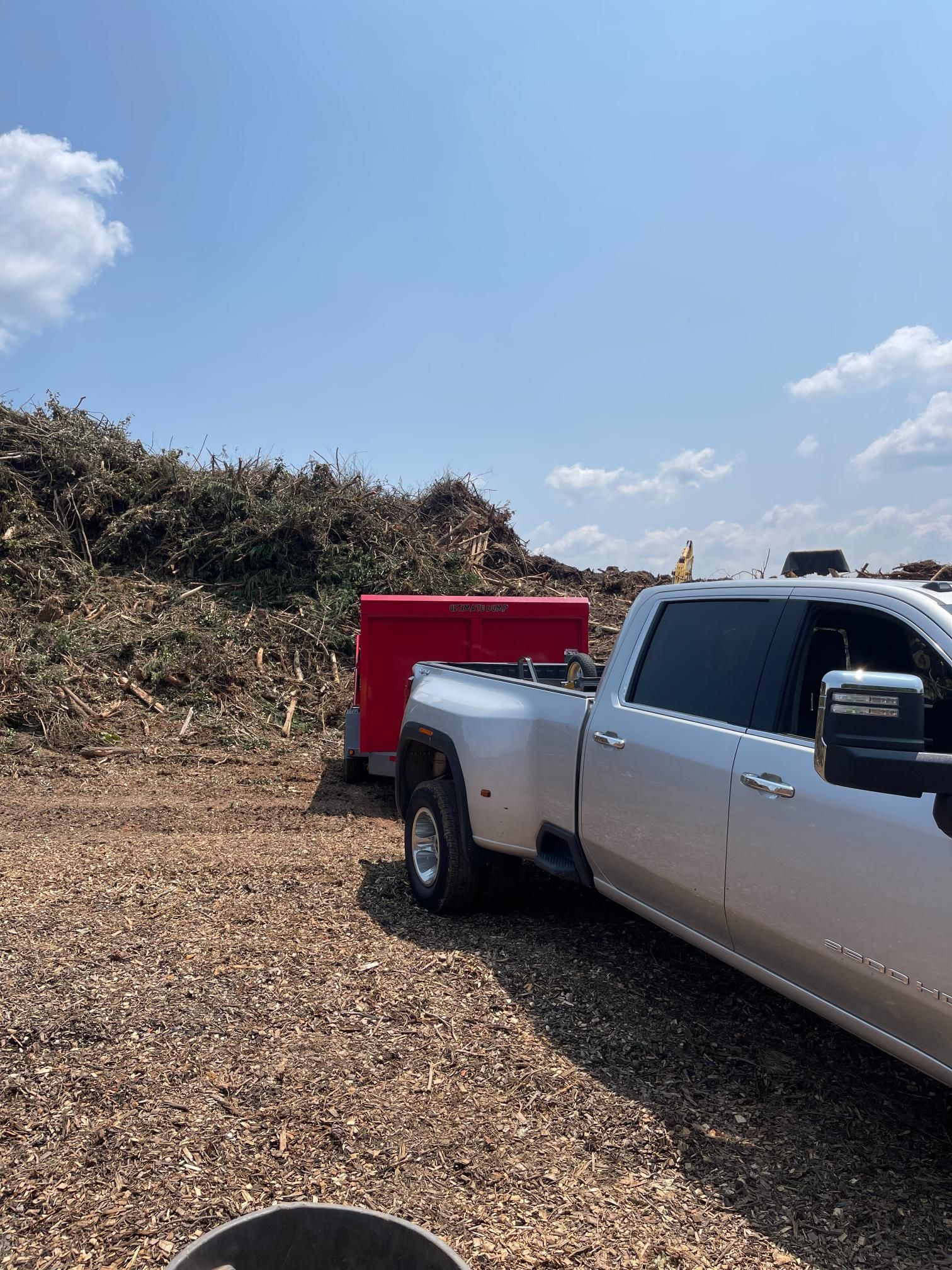 A white truck is towing a red trailer in a dirt field.