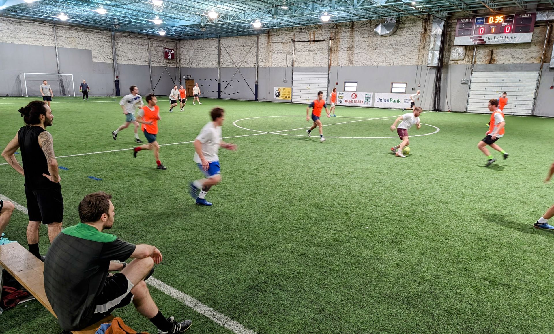 A man in a pink shirt is kicking a soccer ball.