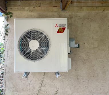 Mitsubishi air conditioning unit mounted on a textured wall.