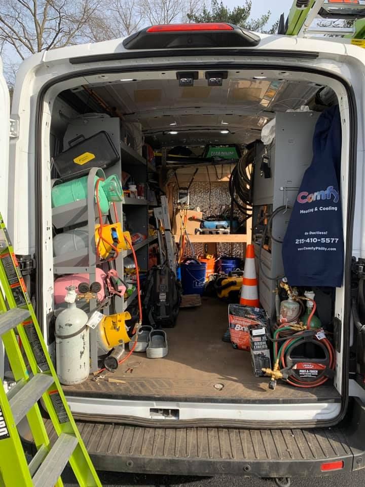 Interior of a white work van with shelves and equipment. Tools and supplies are organized. A ladder is visible.