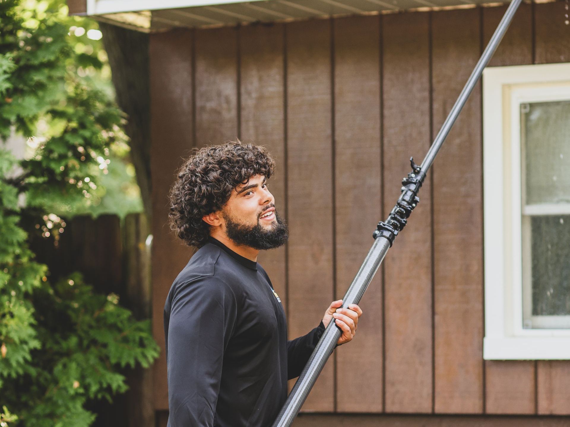 a man with a beard is holding a pole in front of a house