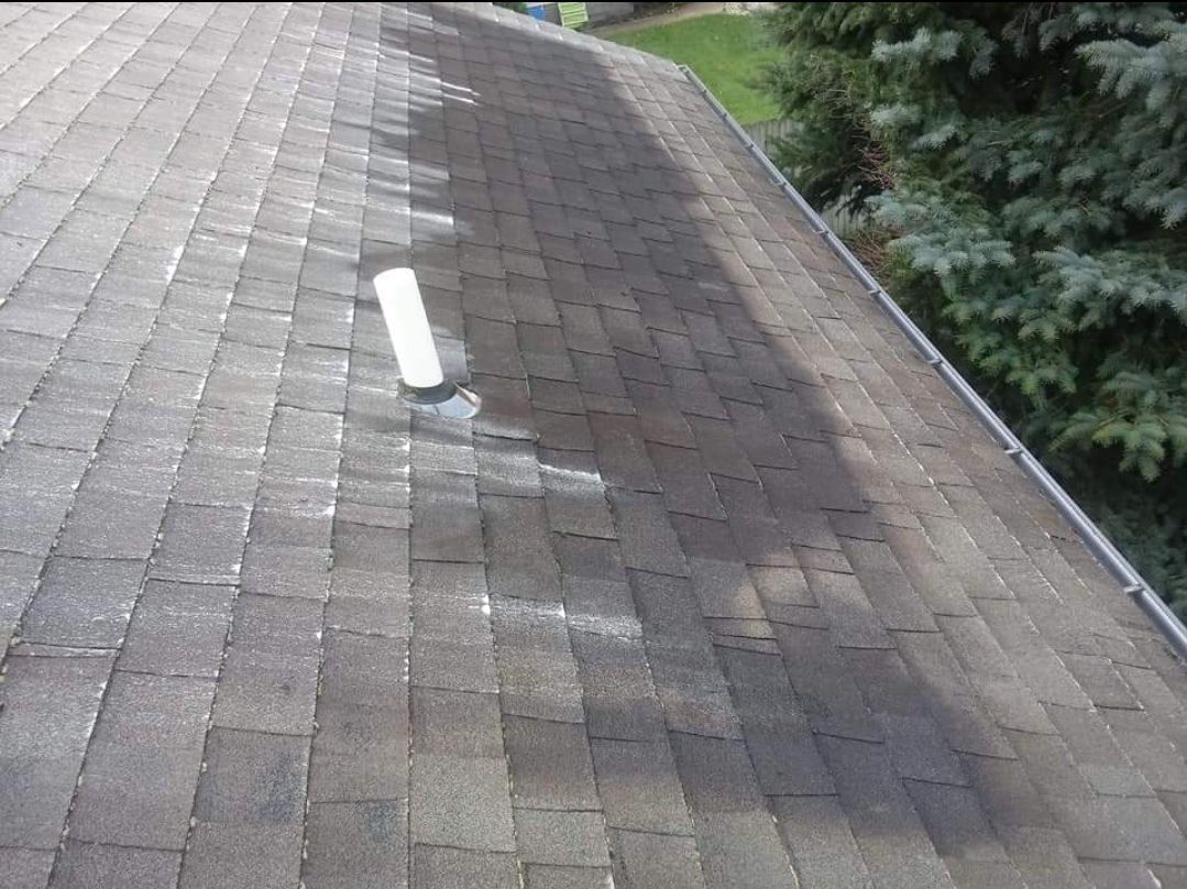 A close up of a roof with a white pipe on it.