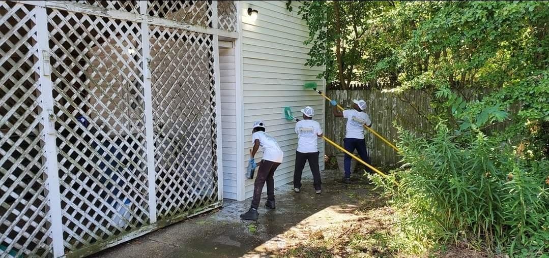 A group of people are cleaning the side of a house.