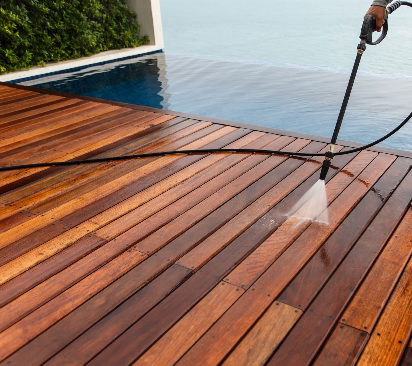 a person is cleaning a wooden deck next to a pool