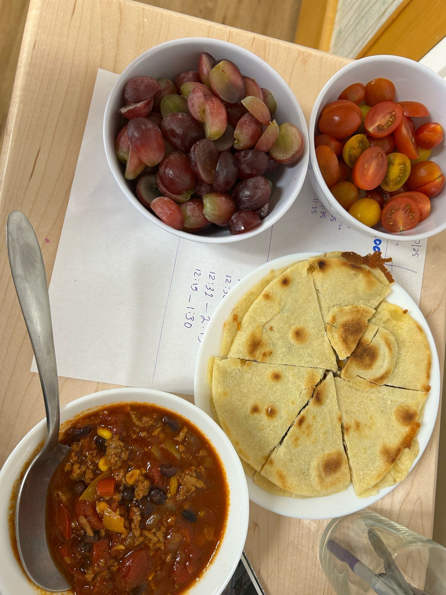 A table topped with bowls of food including grapes and tomatoes