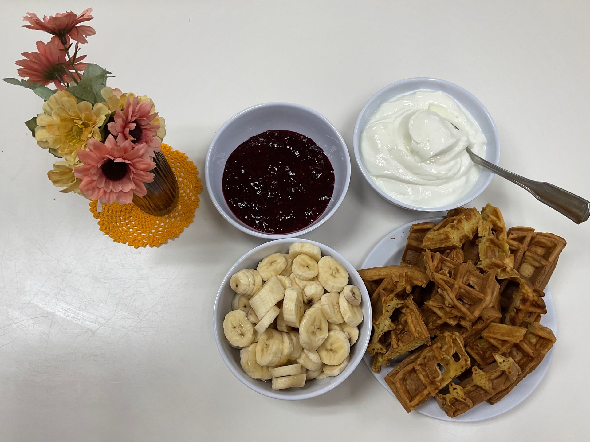 A table topped with bowls of food including waffles bananas and yogurt