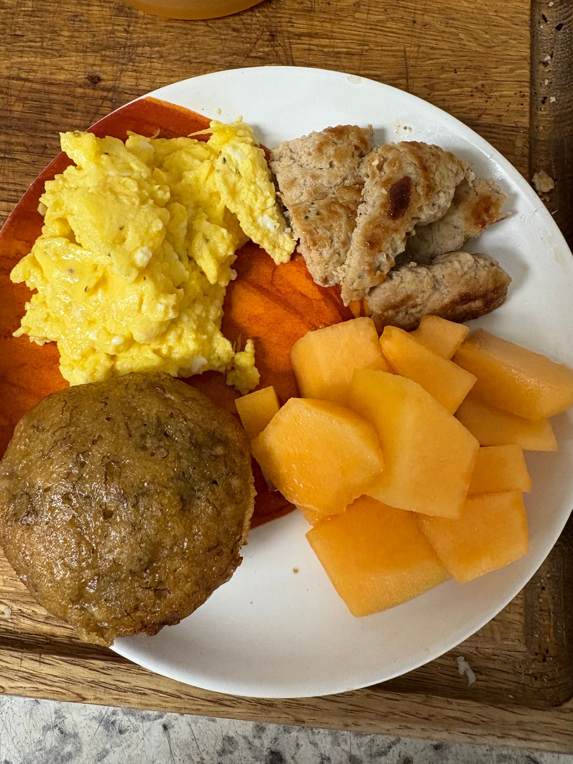 A white plate topped with eggs, meatballs, carrots and cantaloupe.