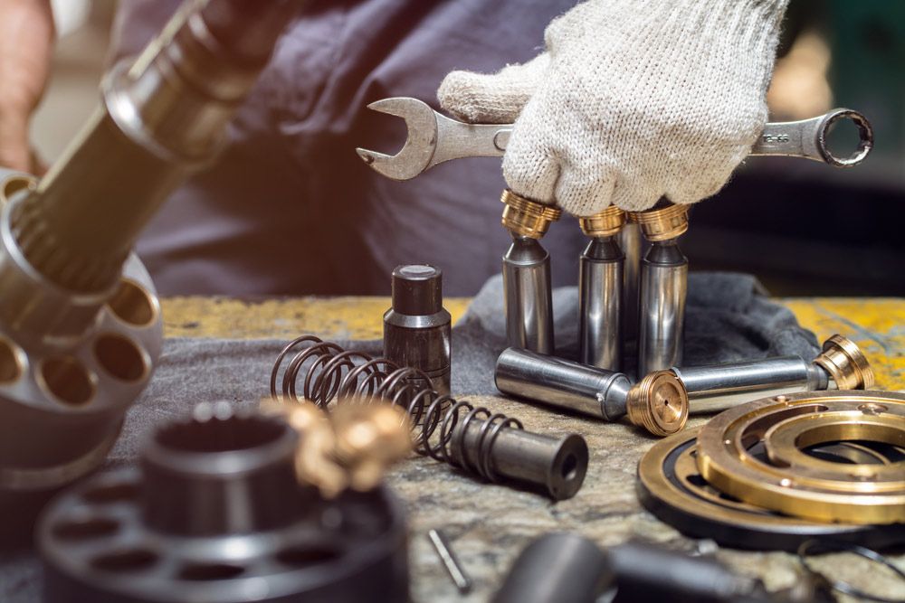 A Man Is Working On A Machine With A Wrench — Wide Bay Hydraulics in Gympie, QLD