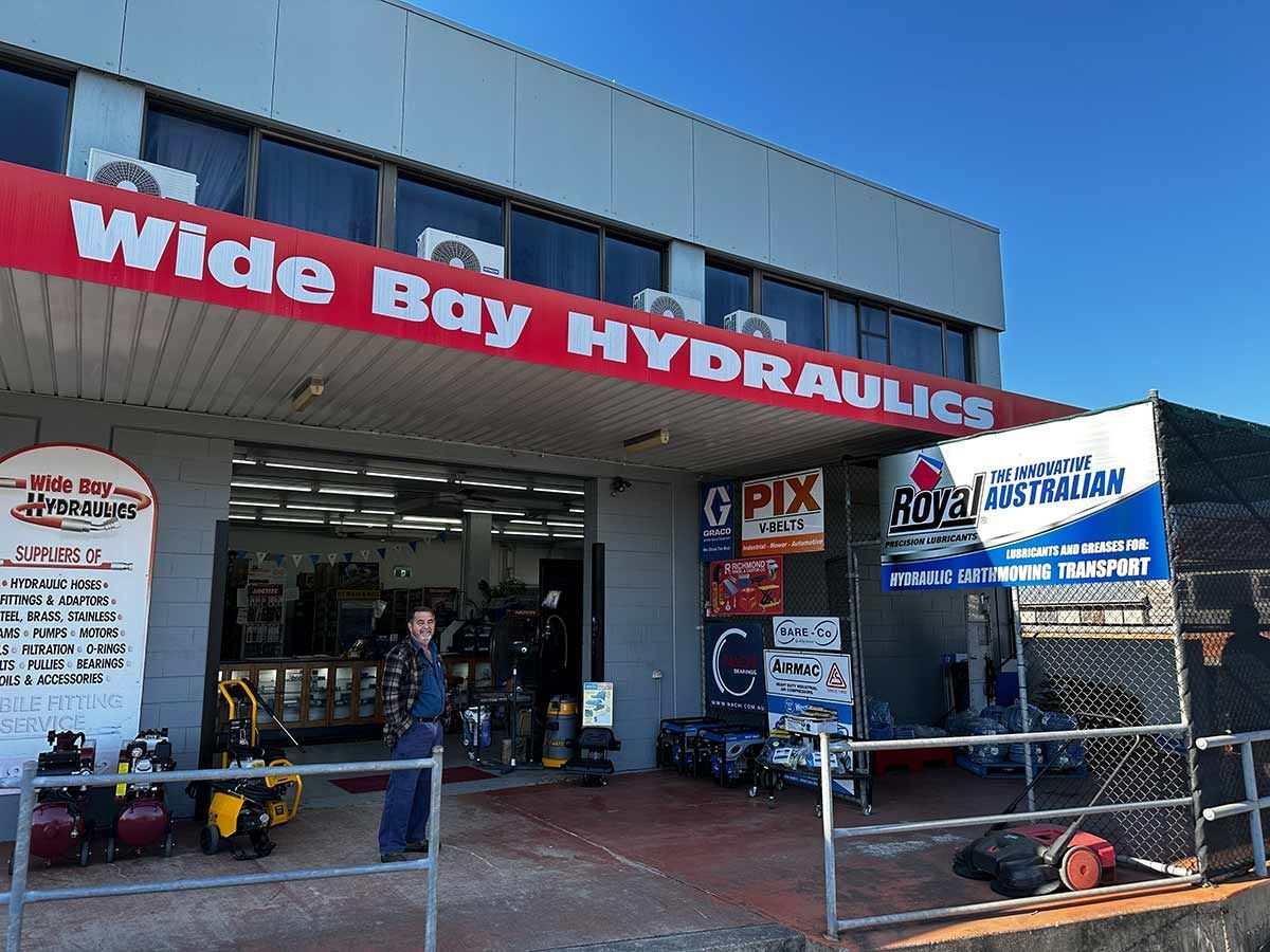 A Man Is Standing Outside Of Wide Bay Hydraulics — Wide Bay Hydraulics in Gympie, QLD