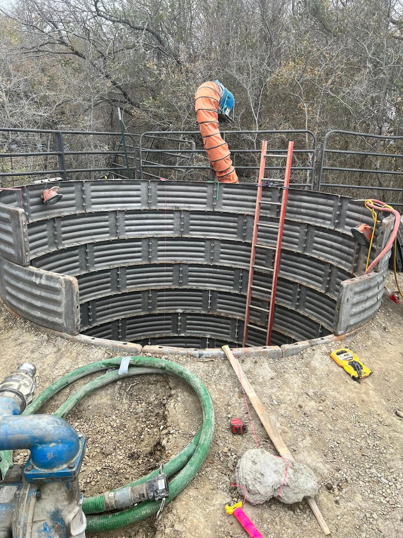 Construction site with a circular structure being built, brown, with ladders and equipment.