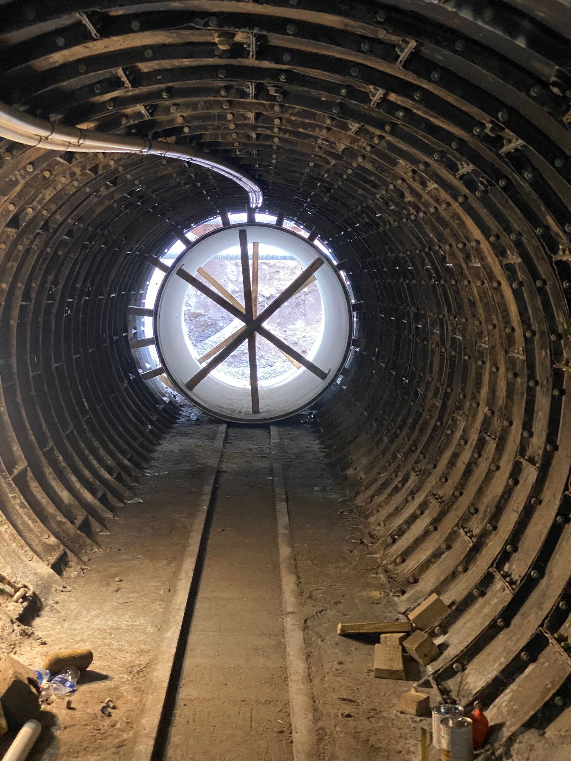 Tunnel interior with black ribbed walls, white substance, and a ladder in the distance.