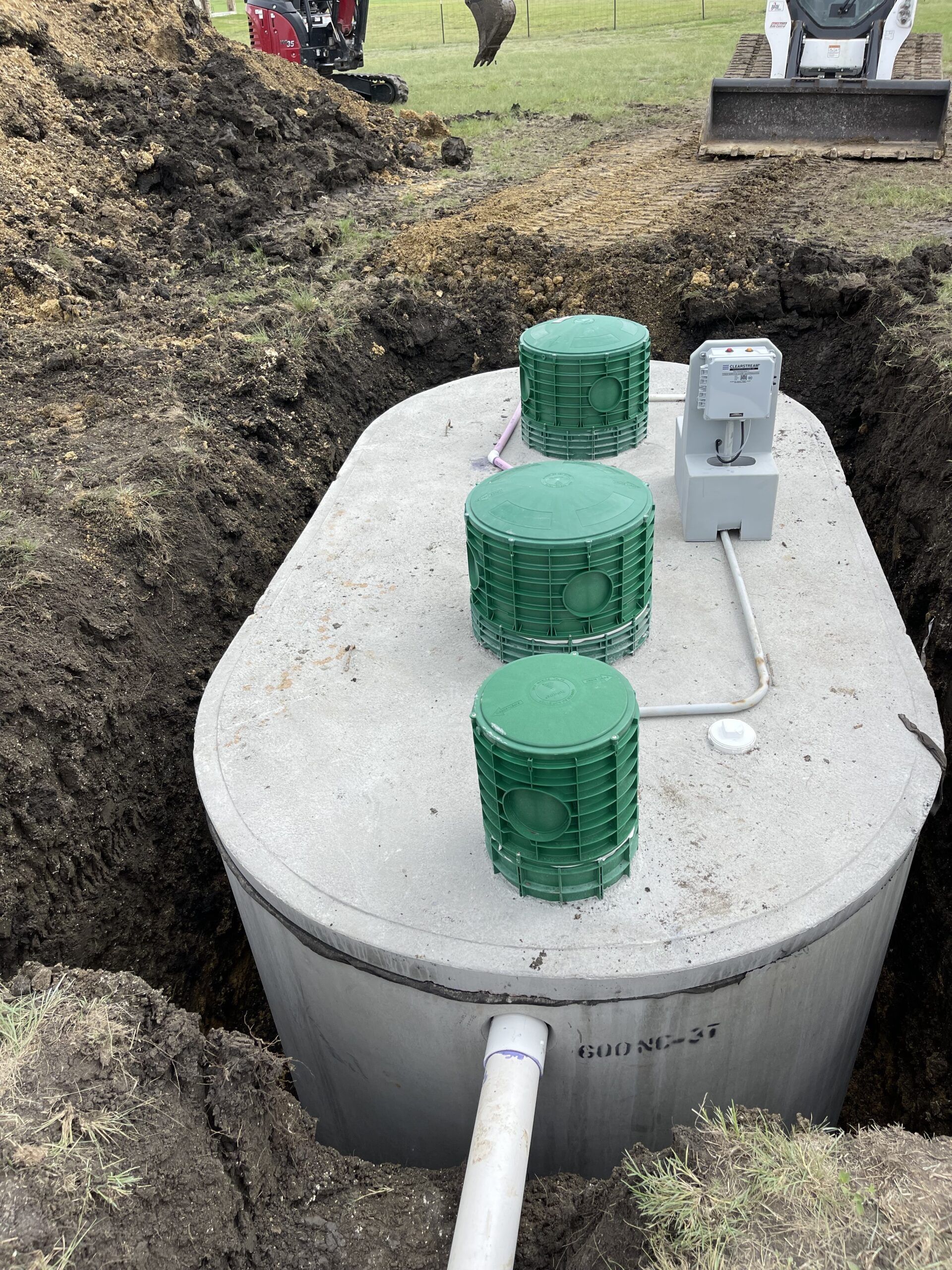 Looking down into a cylindrical tank with liquid inside, a scooping tool is positioned over the liquid.