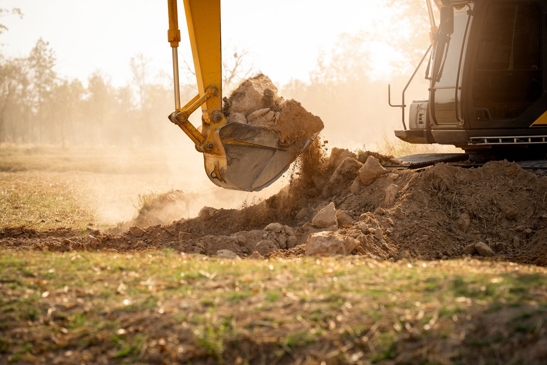 Yellow excavator digging dirt in a field under a bright, sunny sky.