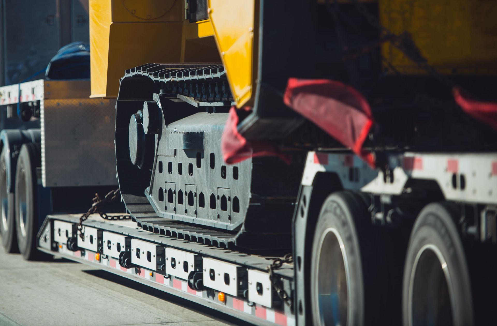 Heavy machinery on a flatbed truck, track tread in detail, yellow and black.
