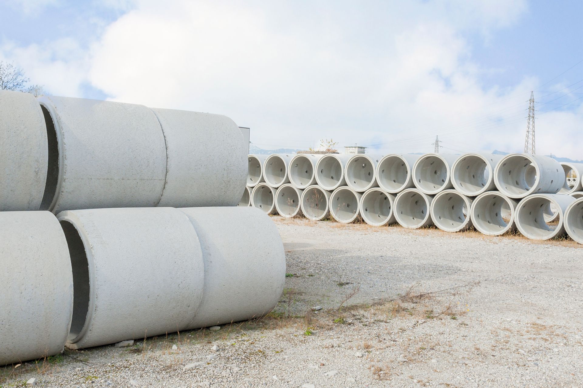 Concrete pipes stacked outdoors against a cloudy sky.