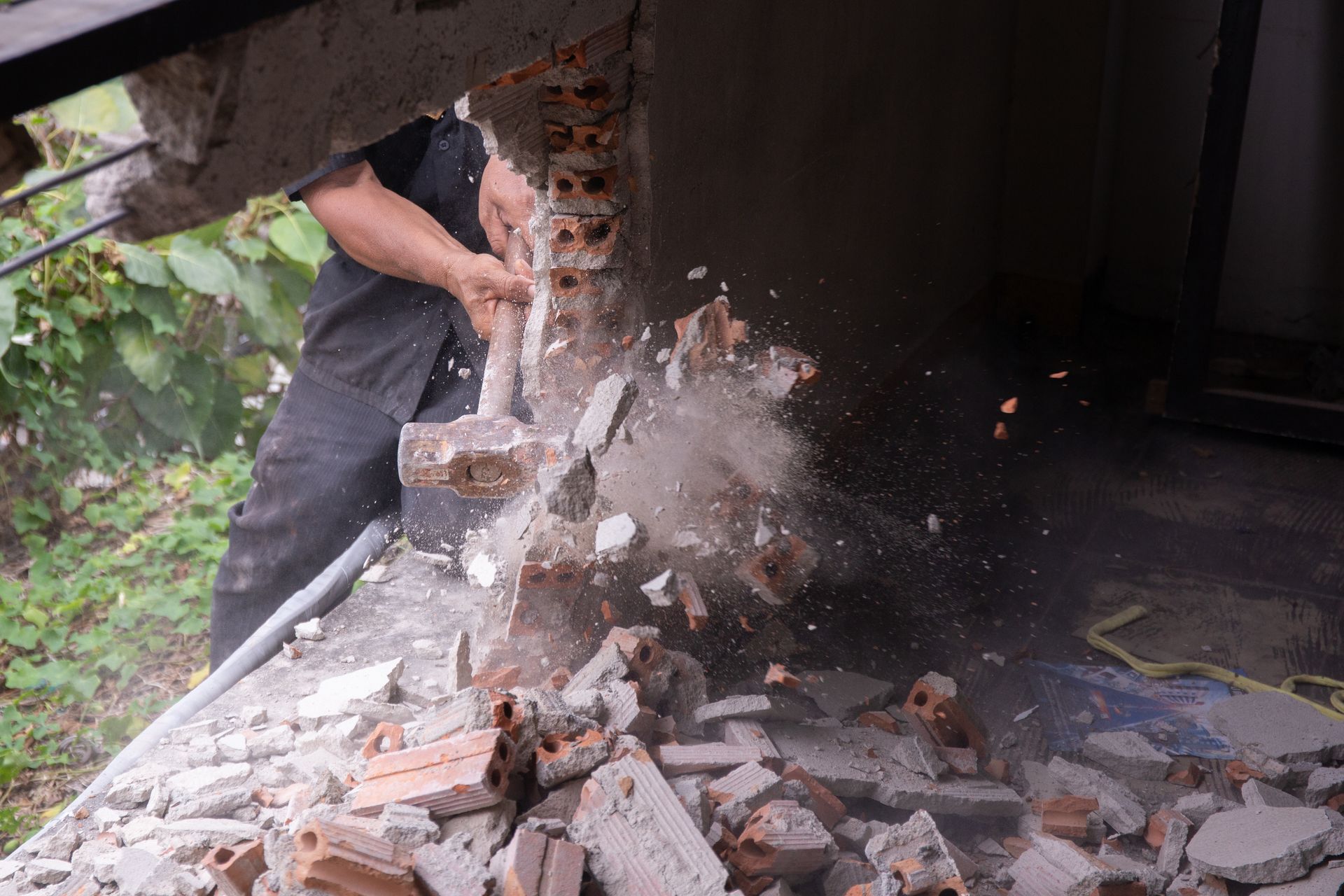 Person demolishing a brick wall, debris flying.