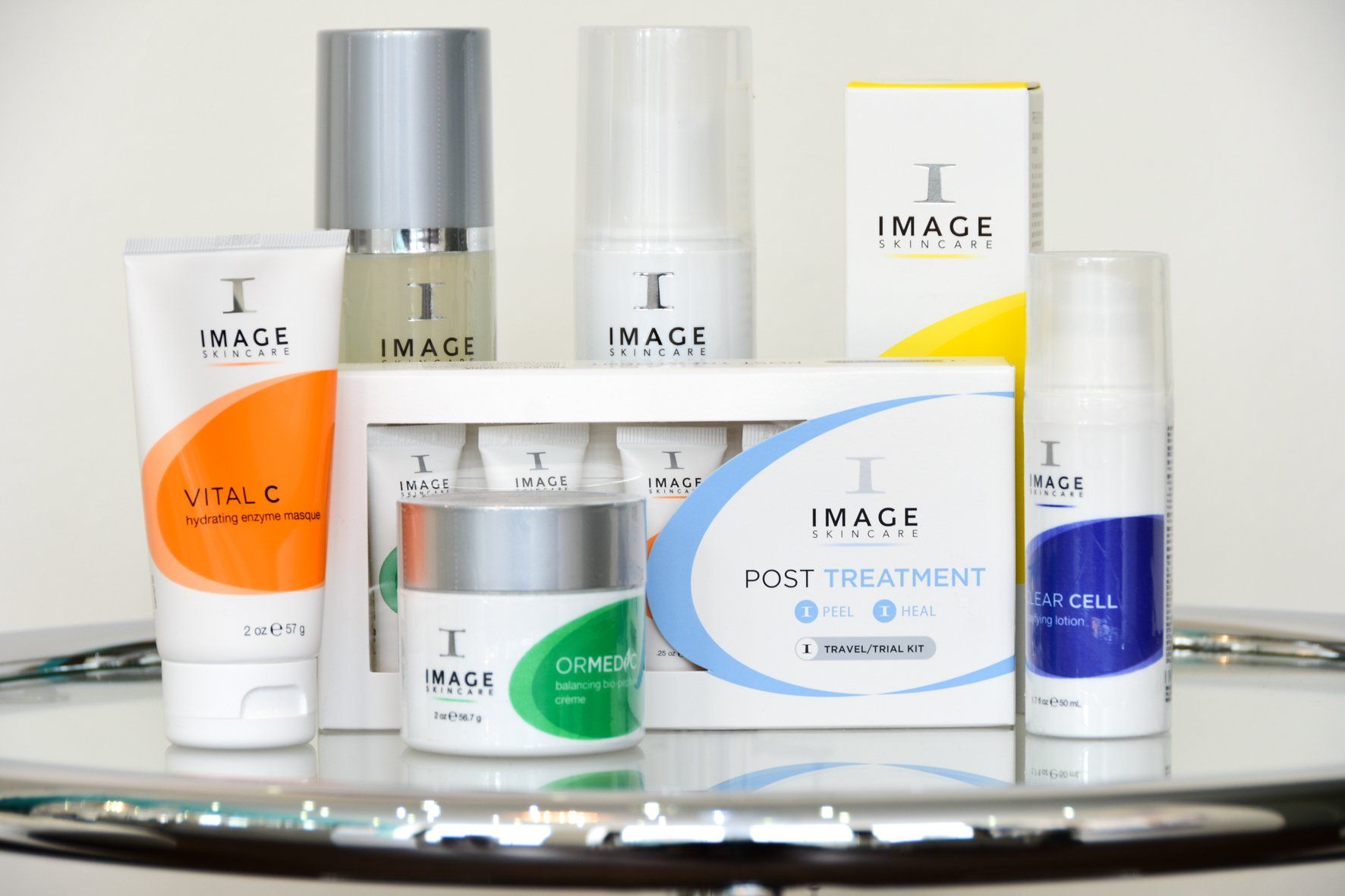 Verschiedene Image Skincare-Produkte, darunter Tuben, Tiegel und Flaschen, werden auf einer reflektierenden Oberfläche präsentiert.