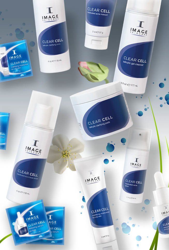 Sortiment an Image Skincare-Produkten in weißer und blauer Verpackung, darunter Reinigungsmittel, Seren und Feuchtigkeitscremes, angeordnet auf einer Oberfläche mit floralen Akzenten und blauen Spritzern.