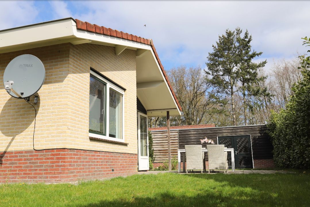 Een klein bakstenen huis met een satellietschotel aan de zijkant.