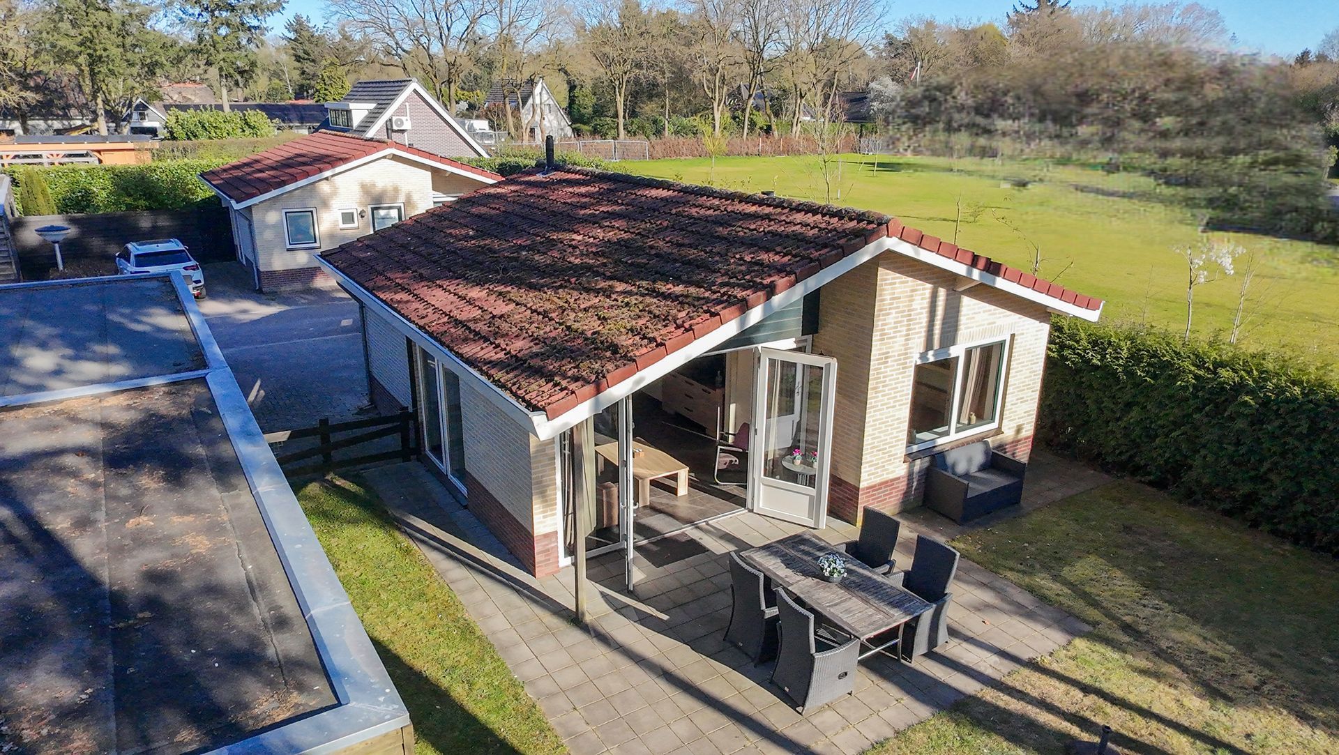 Een luchtfoto van een huis met een tafel en stoelen ervoor.