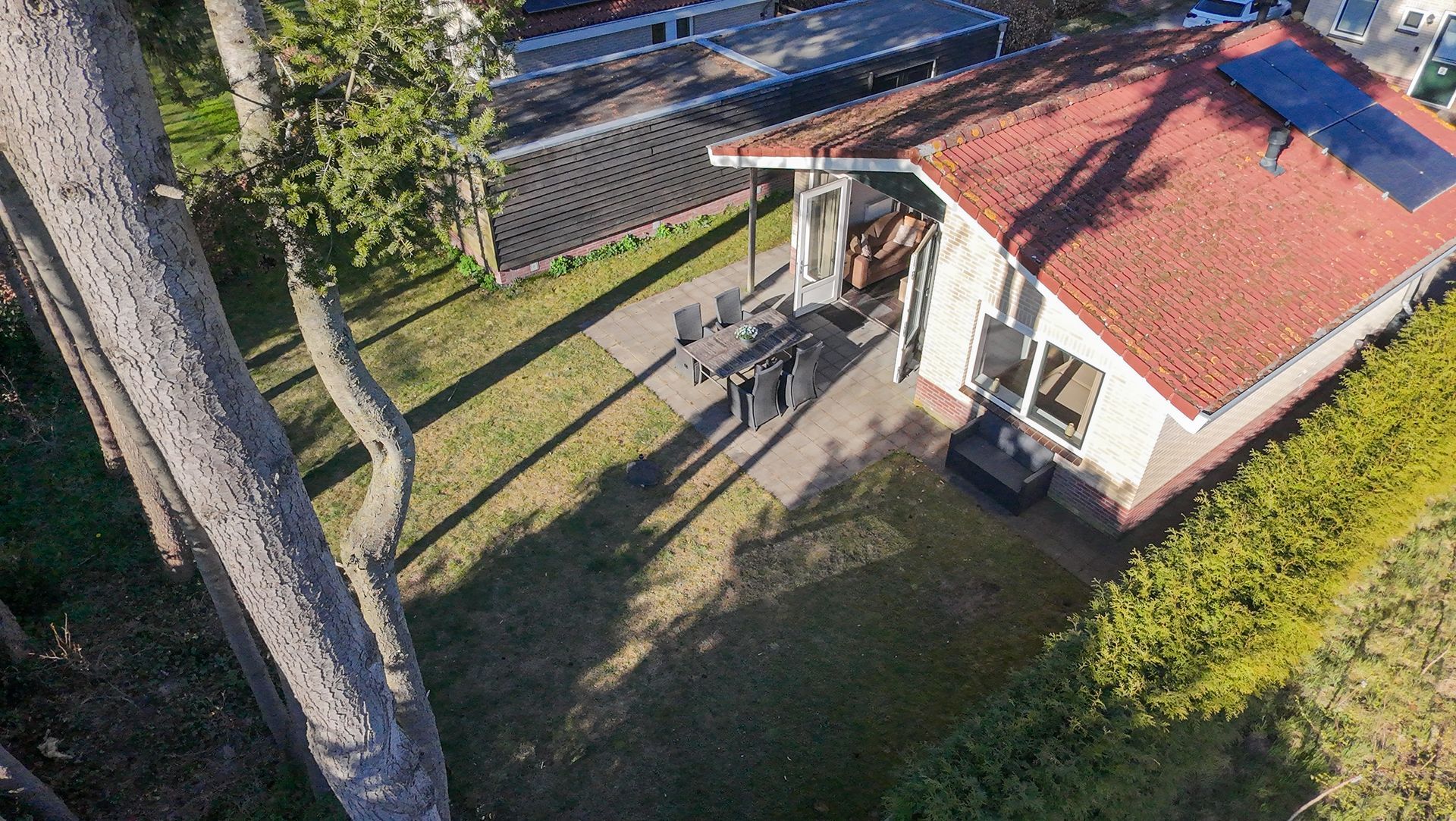 Een luchtfoto van een huis met een rood dak, omgeven door bomen.