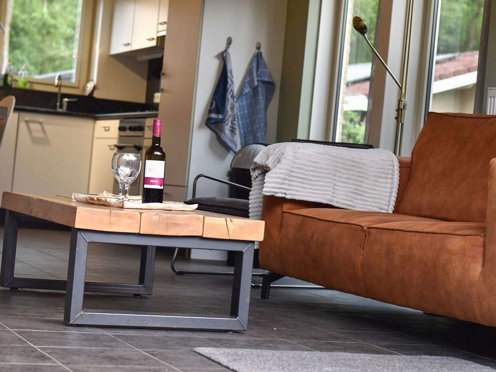 Een woonkamer met een bank en een salontafel met daarop een fles wijn