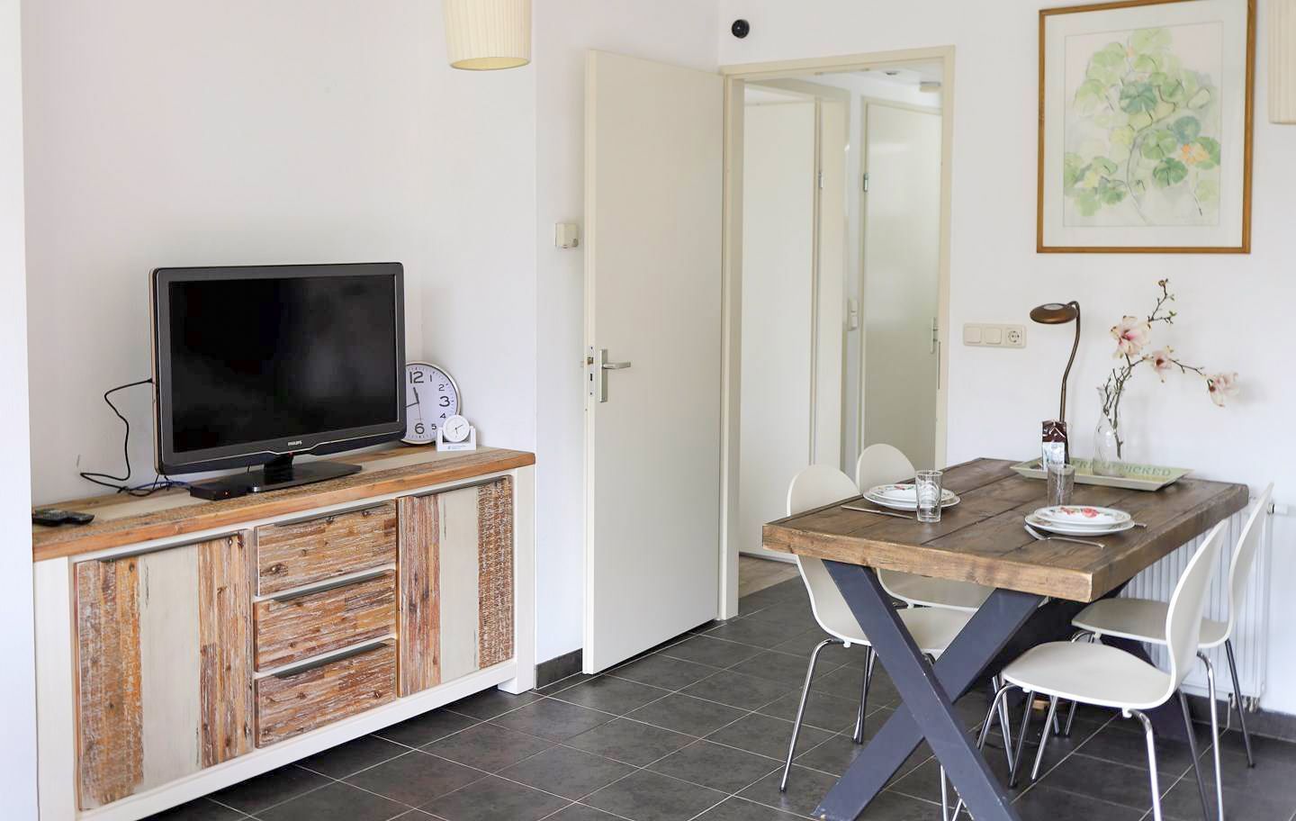 Een woonkamer met een tafel, stoelen en een televisie.