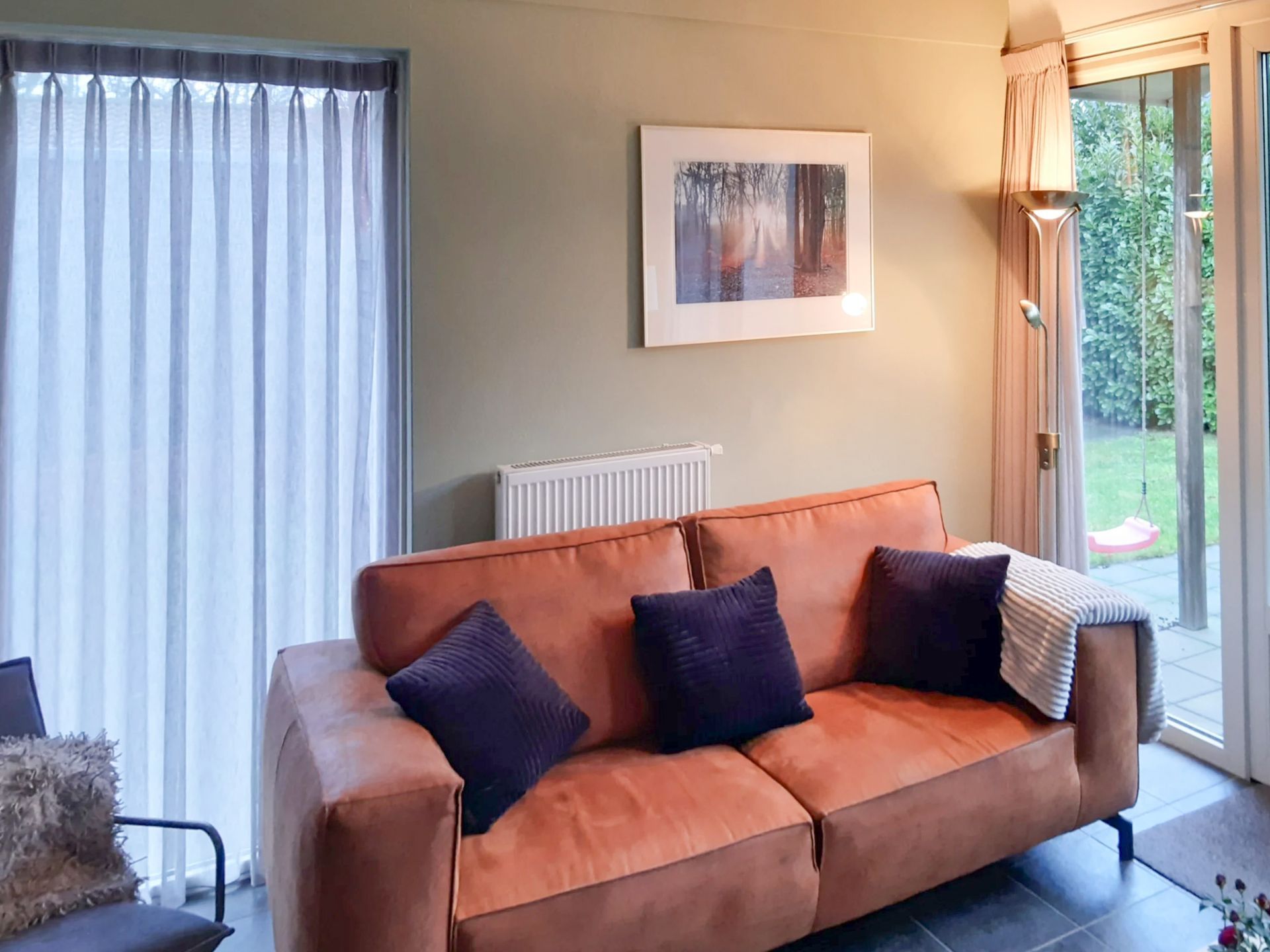 Een woonkamer met een bruine bank en paarse kussens