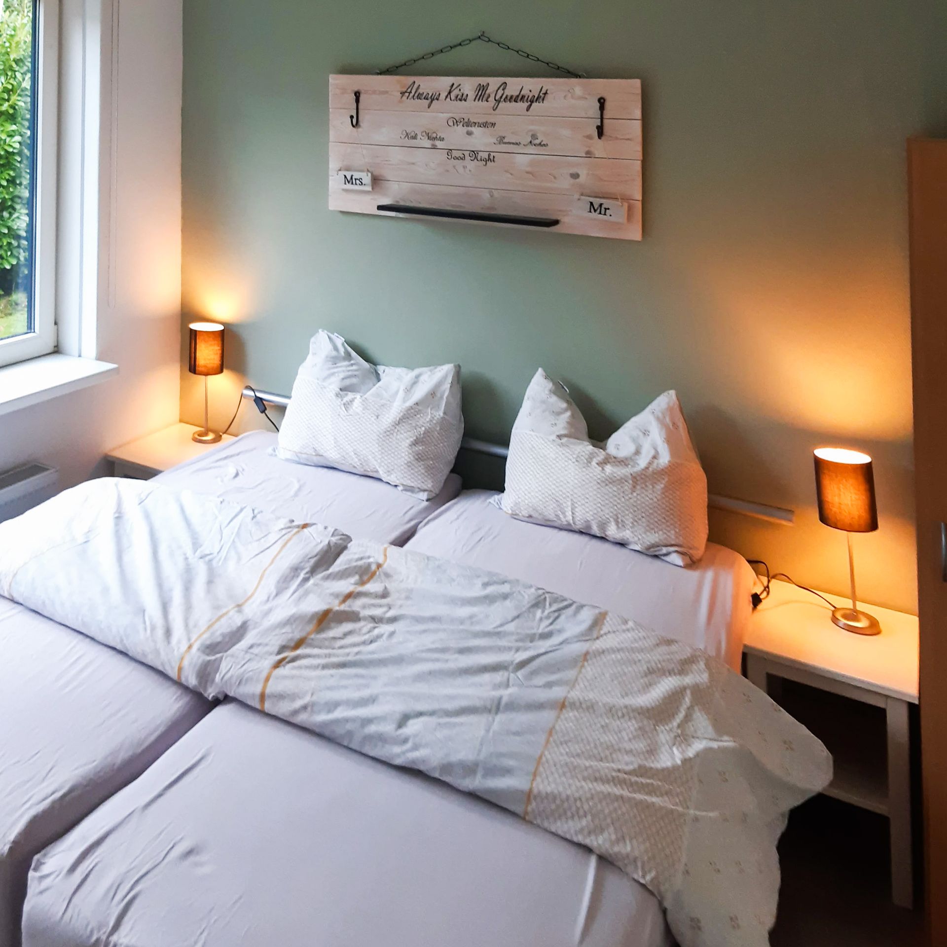 Een slaapkamer met twee bedden en een bord aan de muur