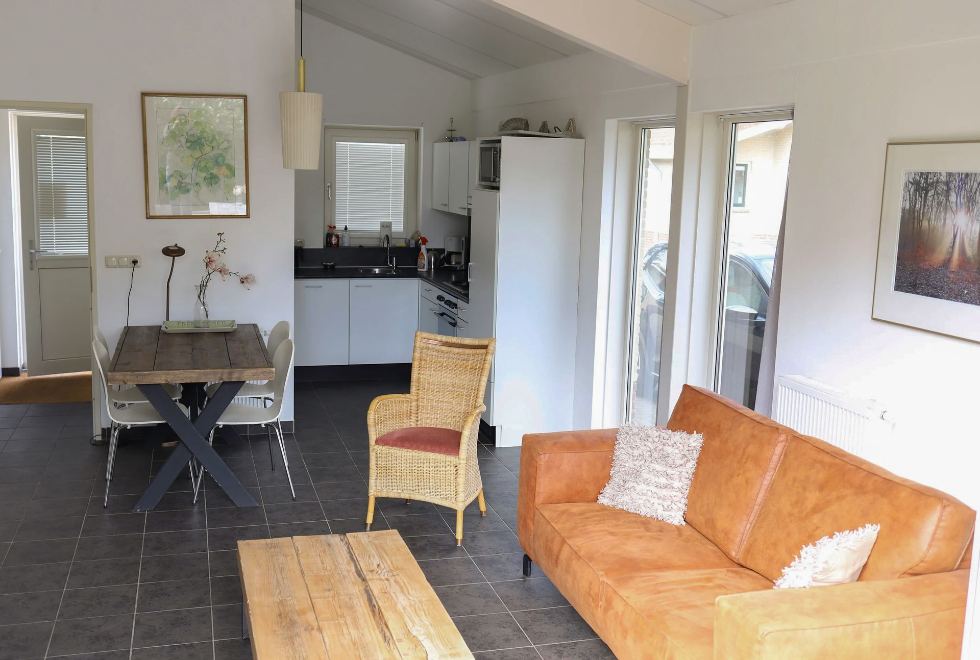 Een woonkamer met een bruine bank en rieten stoelen