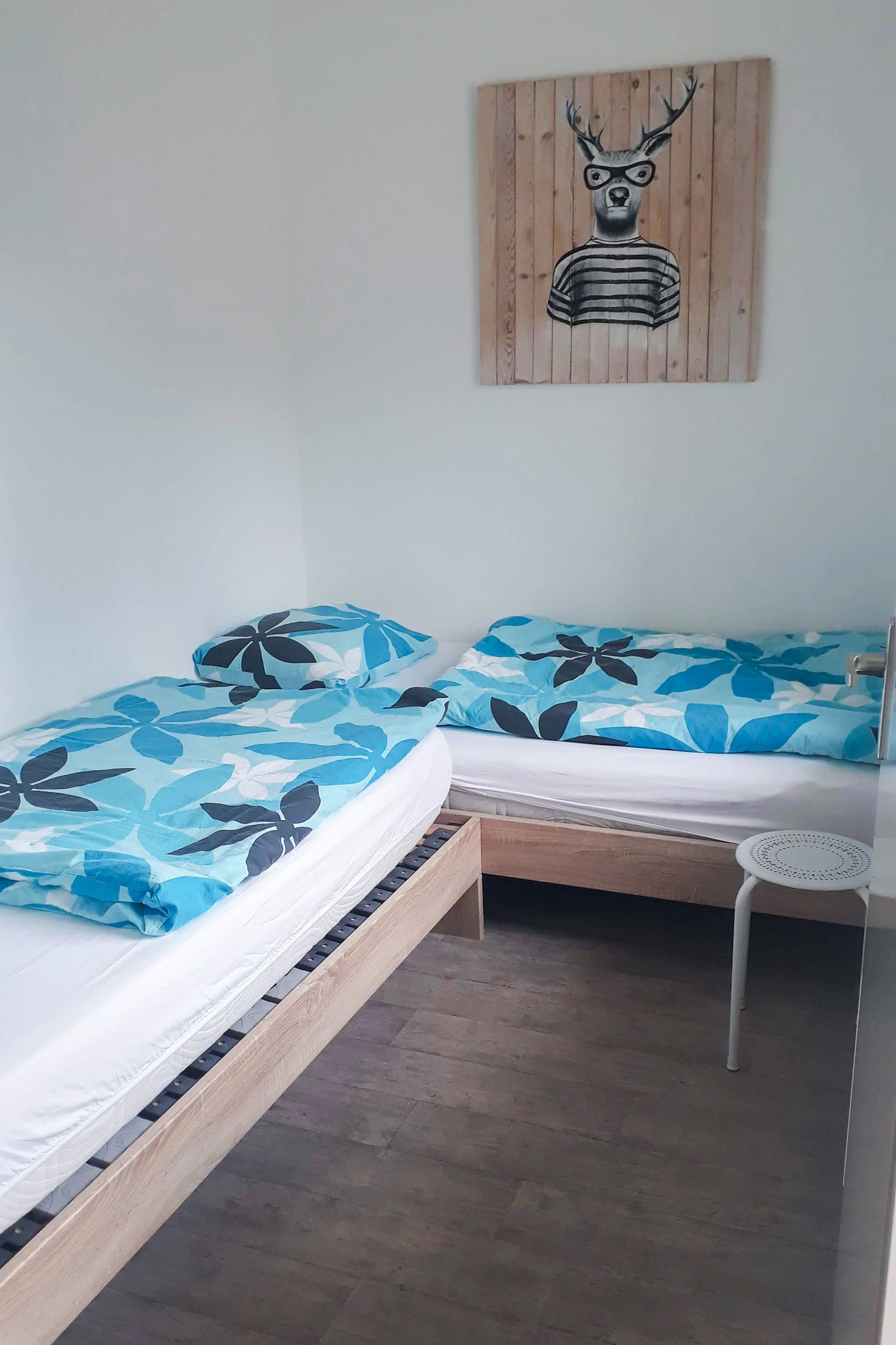 Een slaapkamer met twee bedden en een schilderij van een hert aan de muur.