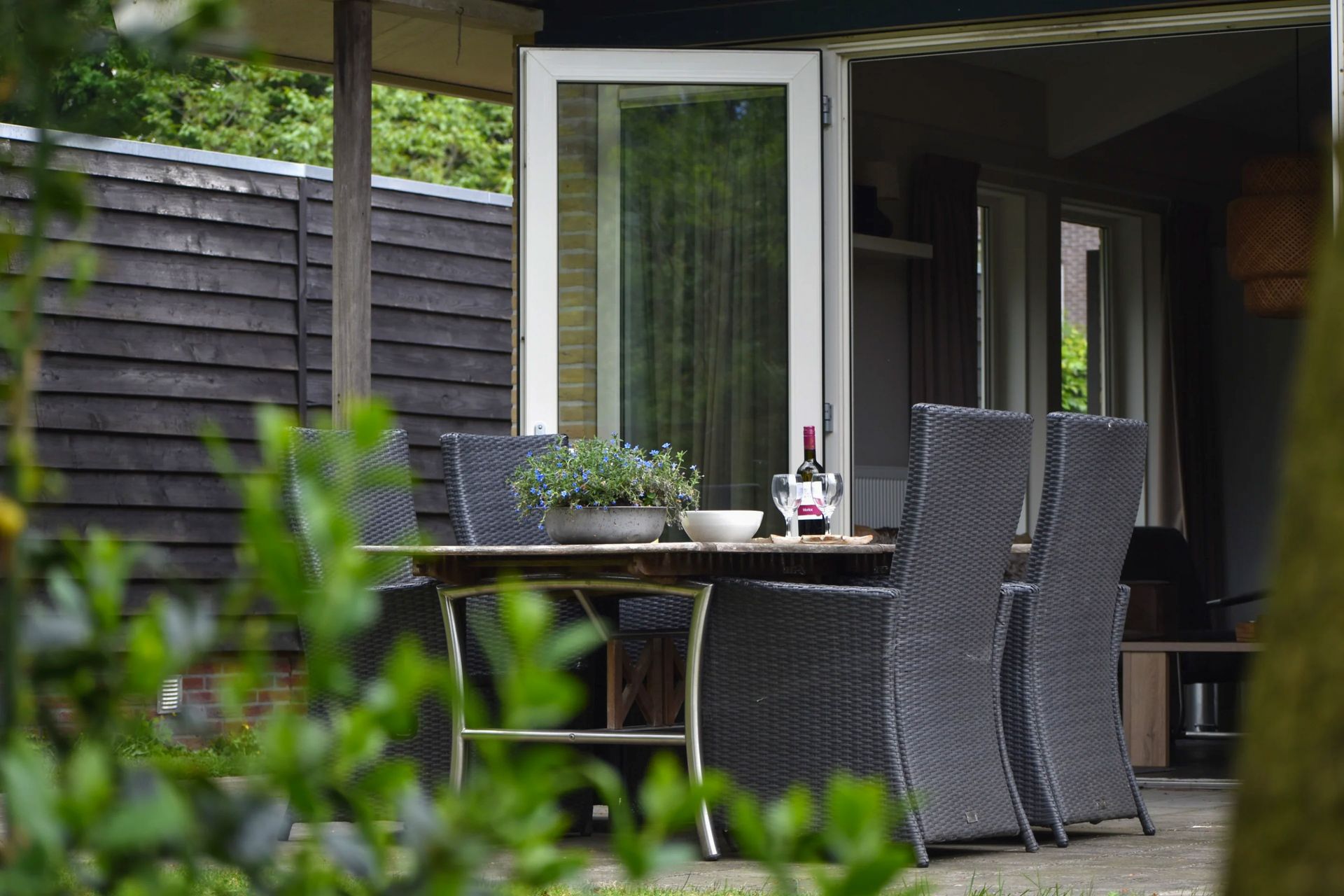 Een terras met een tafel en stoelen voor een huis.