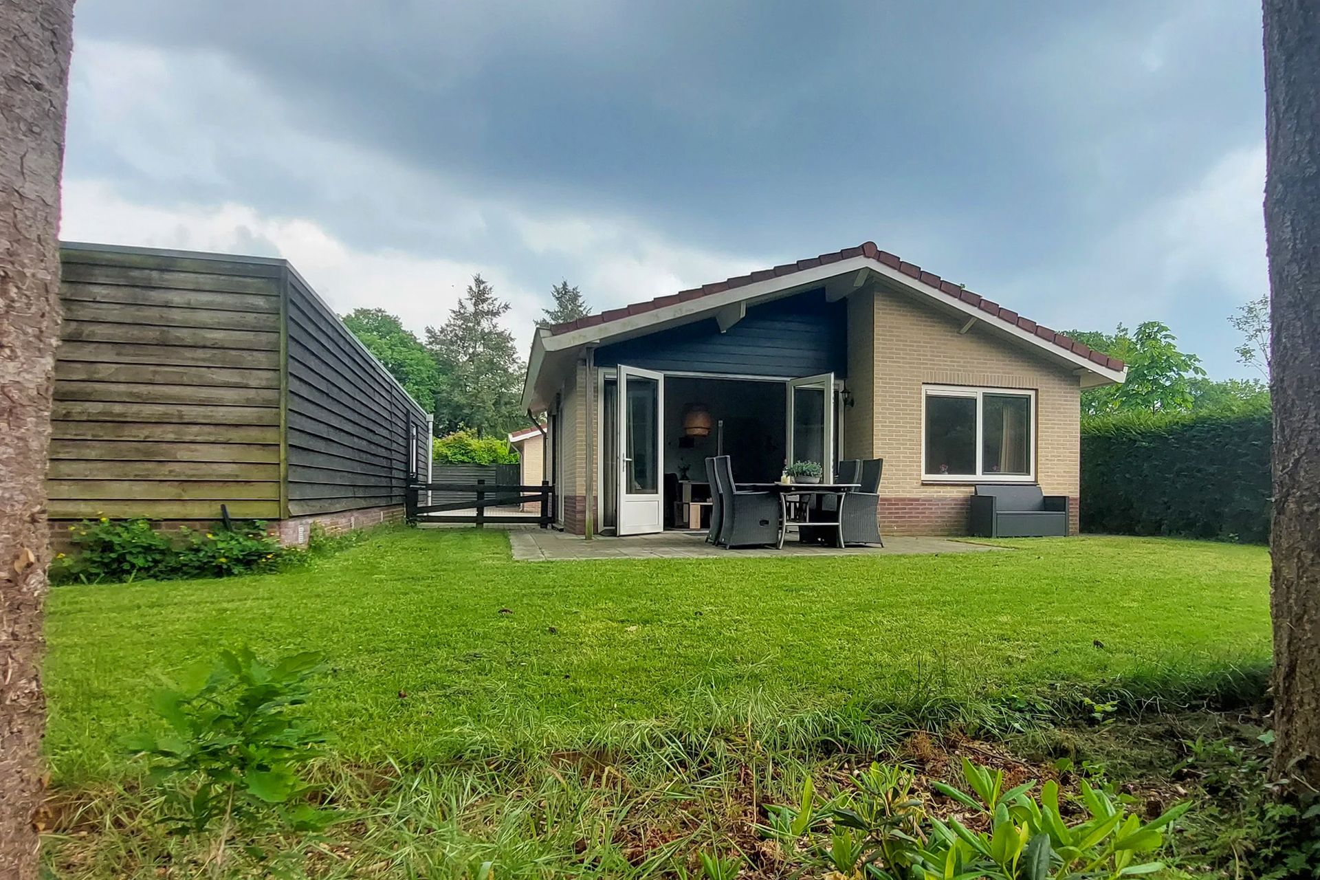 Een klein huisje staat midden in een weelderig groen veld.