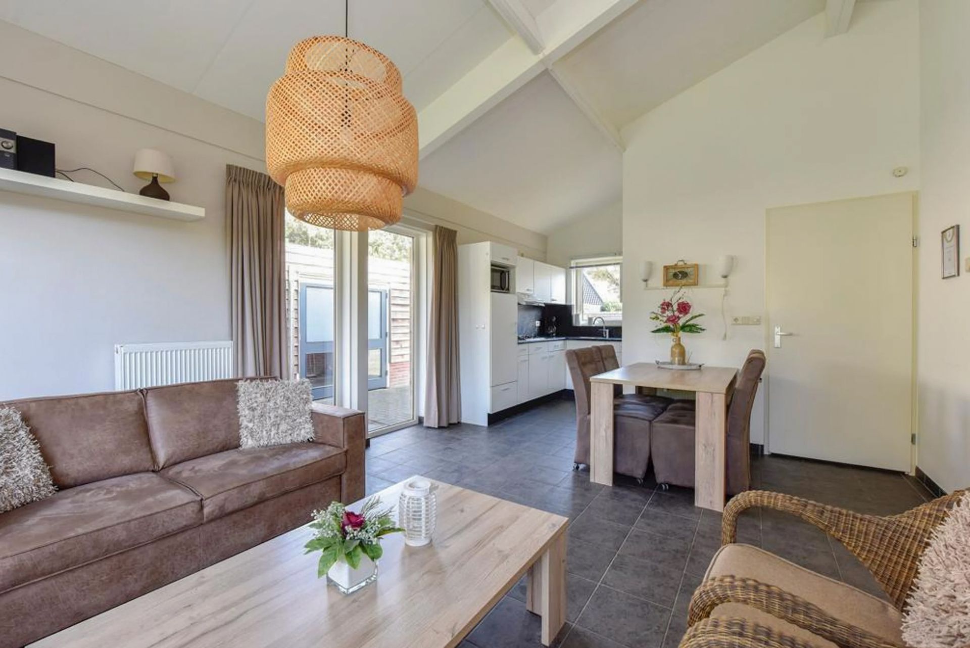 Een woonkamer met een bank, stoelen, een salontafel en een tafel.