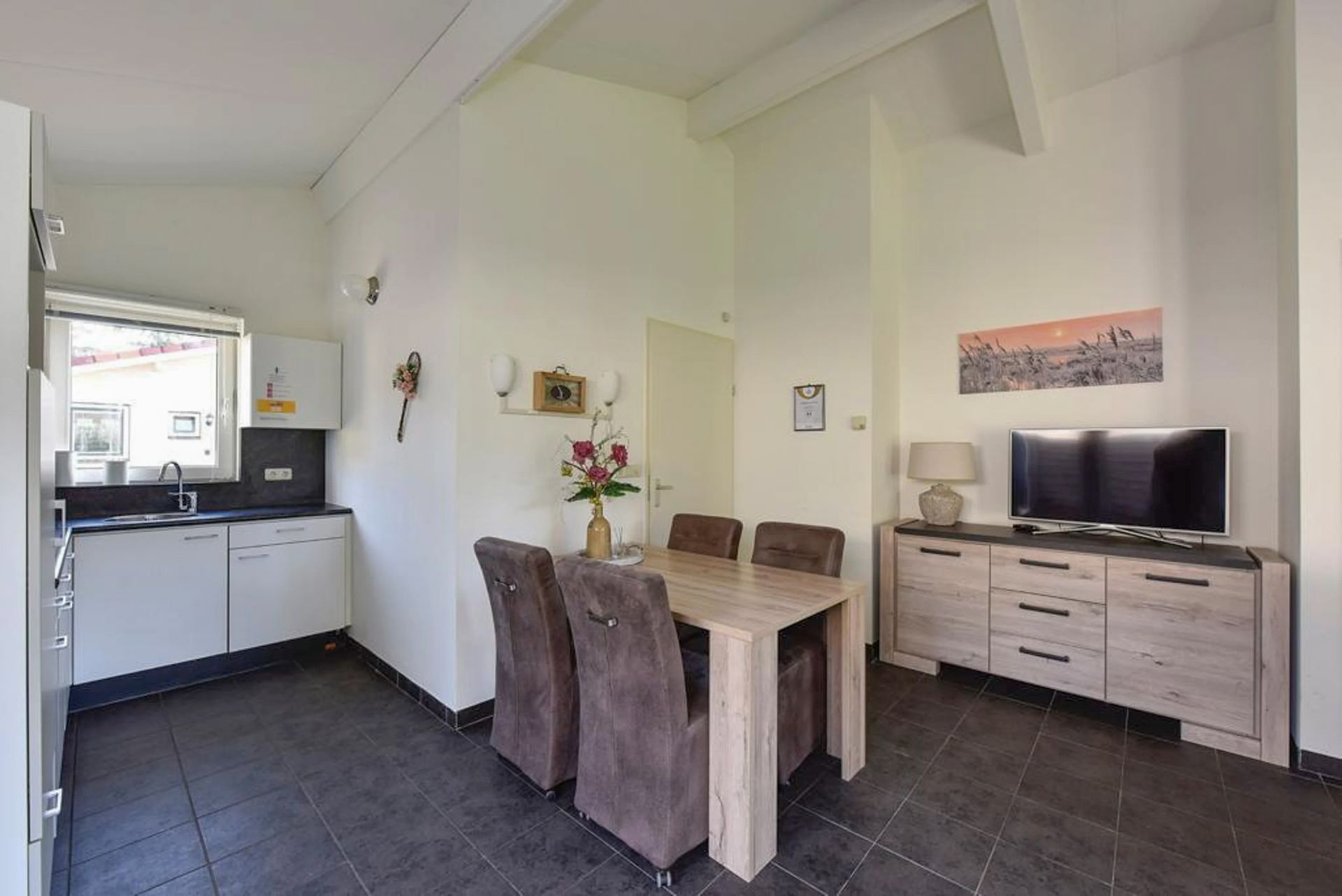 Een woonkamer met een tafel, stoelen en een televisie.