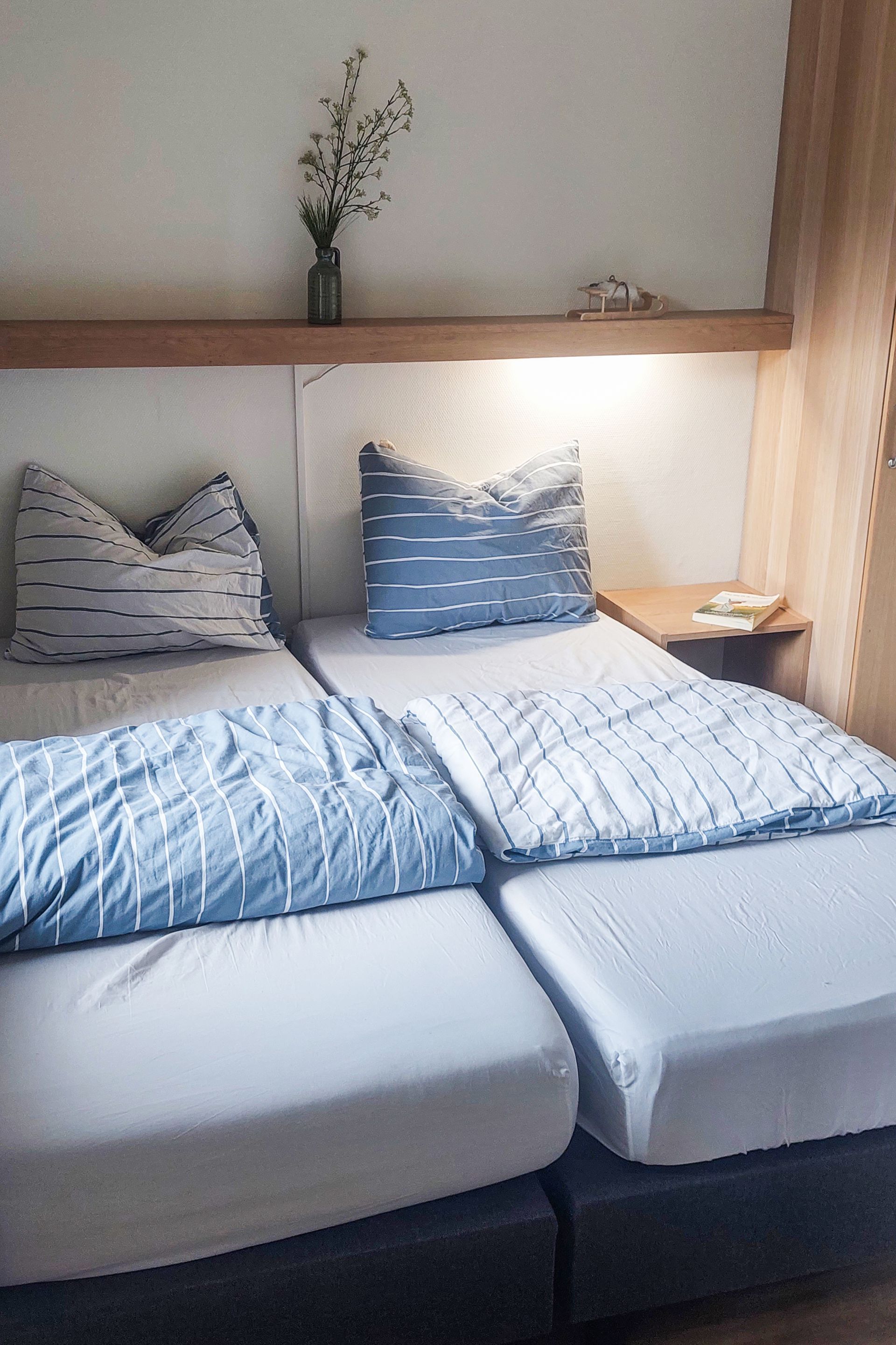 Een slaapkamer met twee bedden en een vaas met bloemen aan de muur