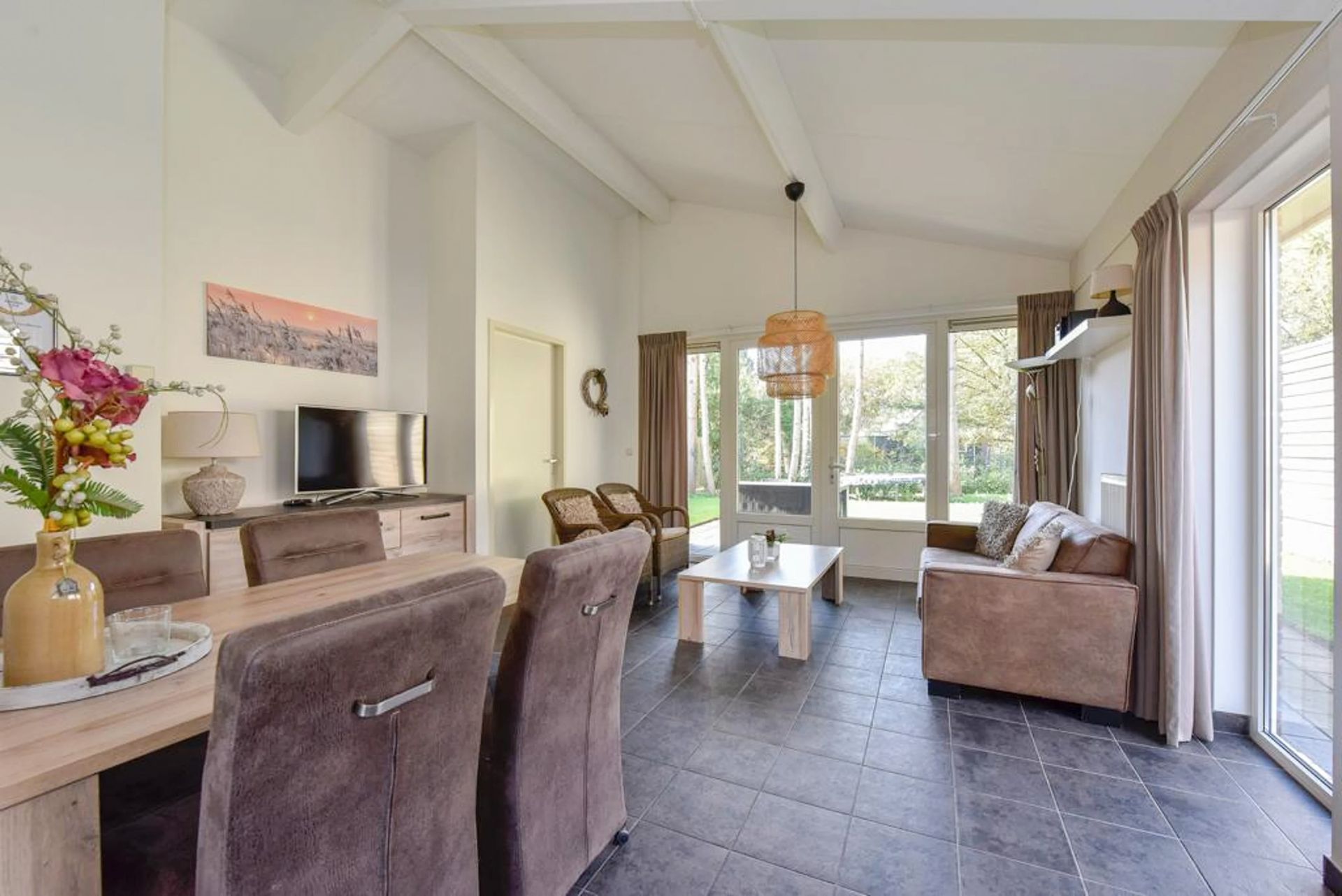 Een woonkamer met een bank, tafel, stoelen en een televisie.