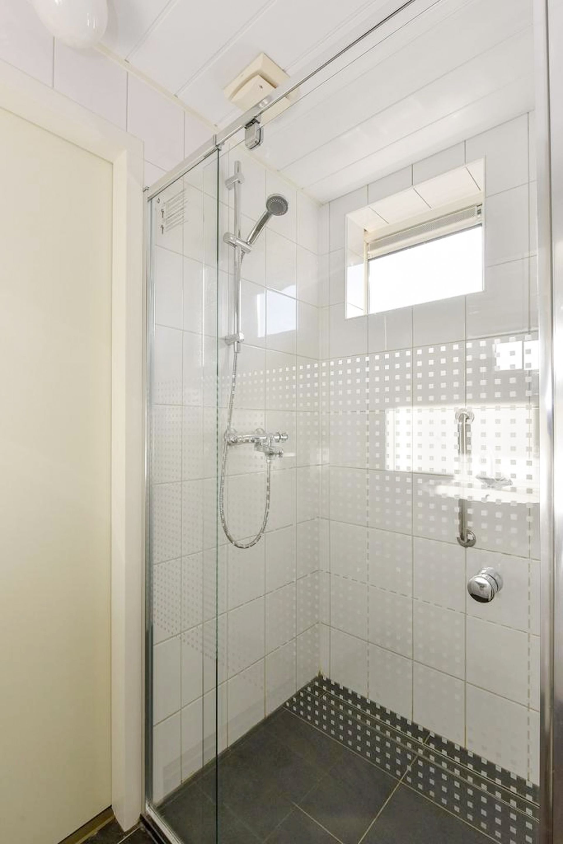 Een badkamer met inloopdouche en een raam.