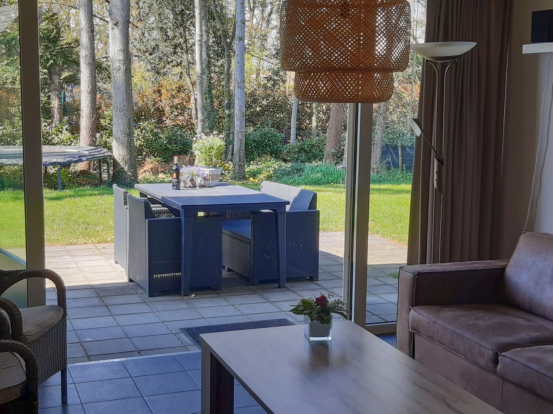 Een woonkamer met een bank, tafel, stoelen en uitzicht op een terras.