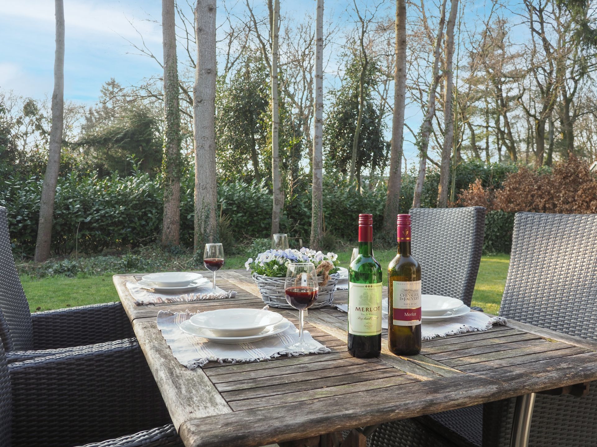 Twee flessen wijn staan ​​op een houten tafel buiten