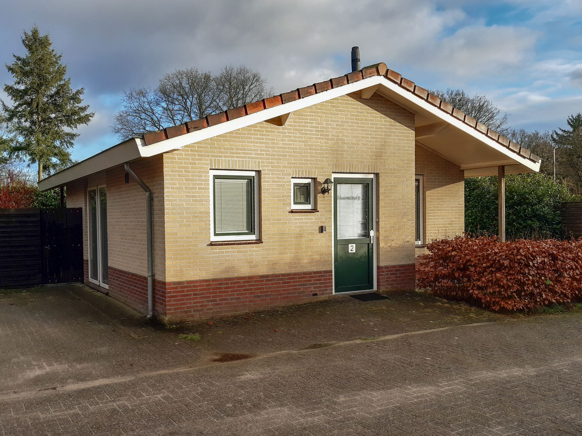 Een klein bakstenen huis met een groene deur en ramen
