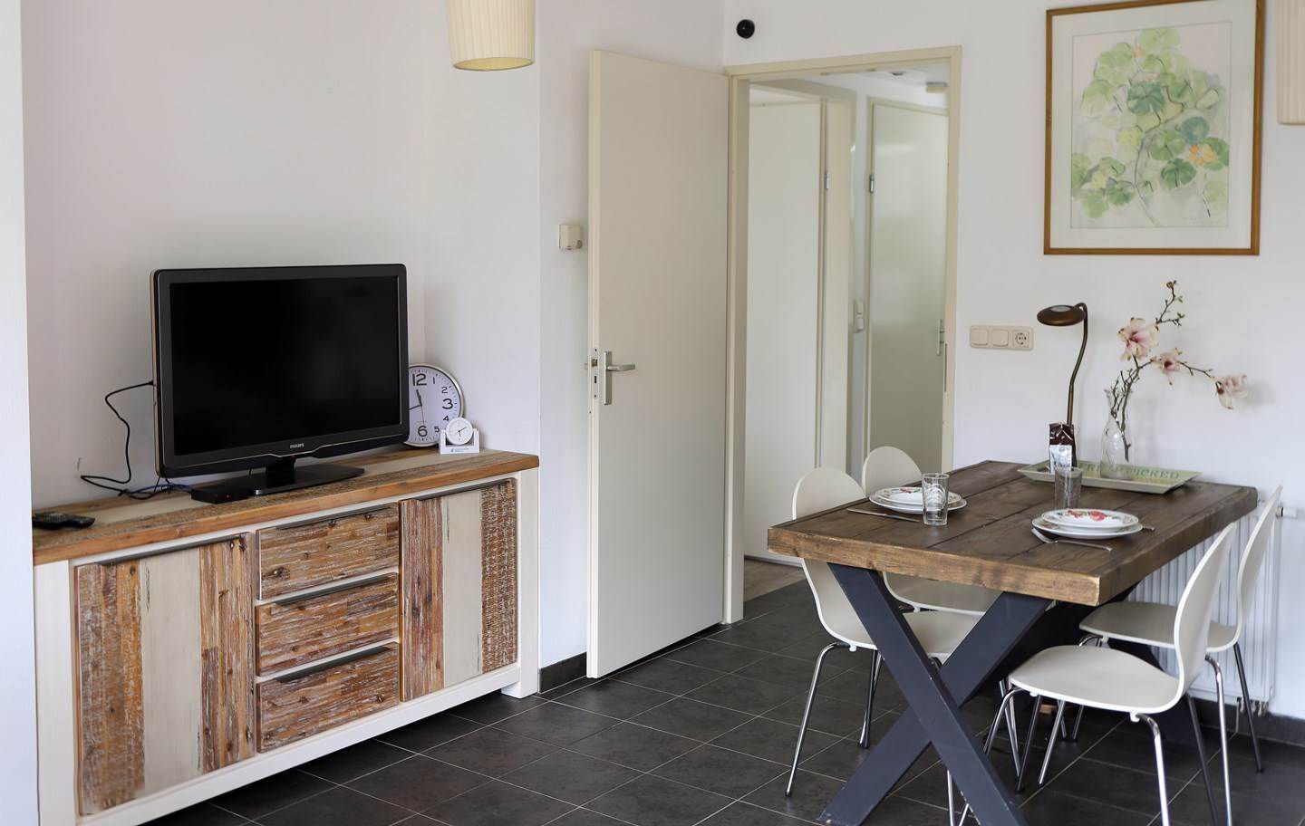 Een woonkamer met een tafel, stoelen en een televisie.