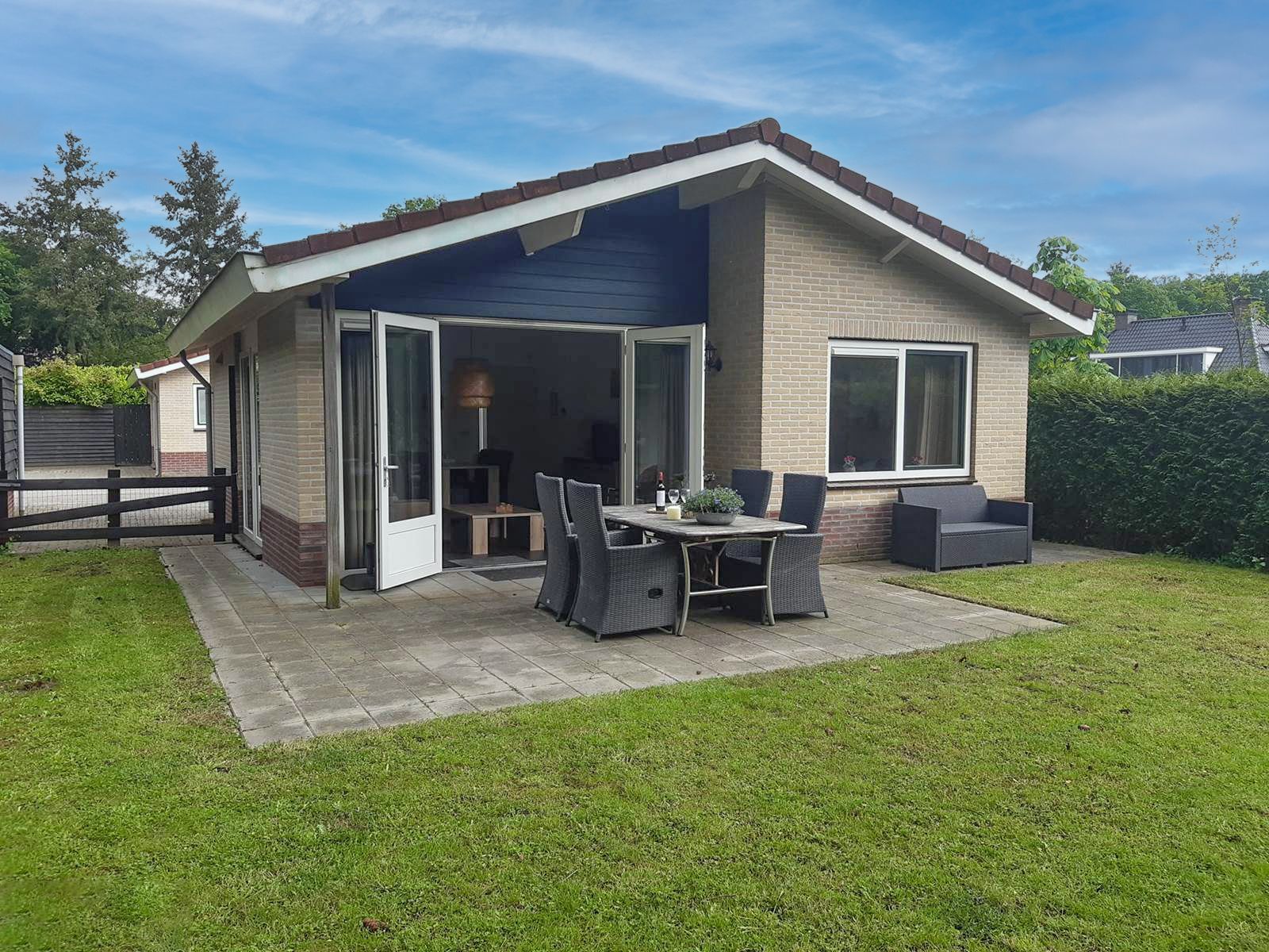 Een klein huisje met een tafel en stoelen ervoor.