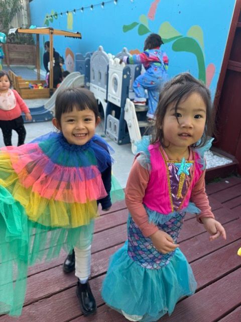 A boy and a girl dressed in costumes are standing next to each other on a wooden deck.