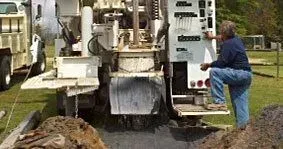 A man is kneeling in front of a truck.