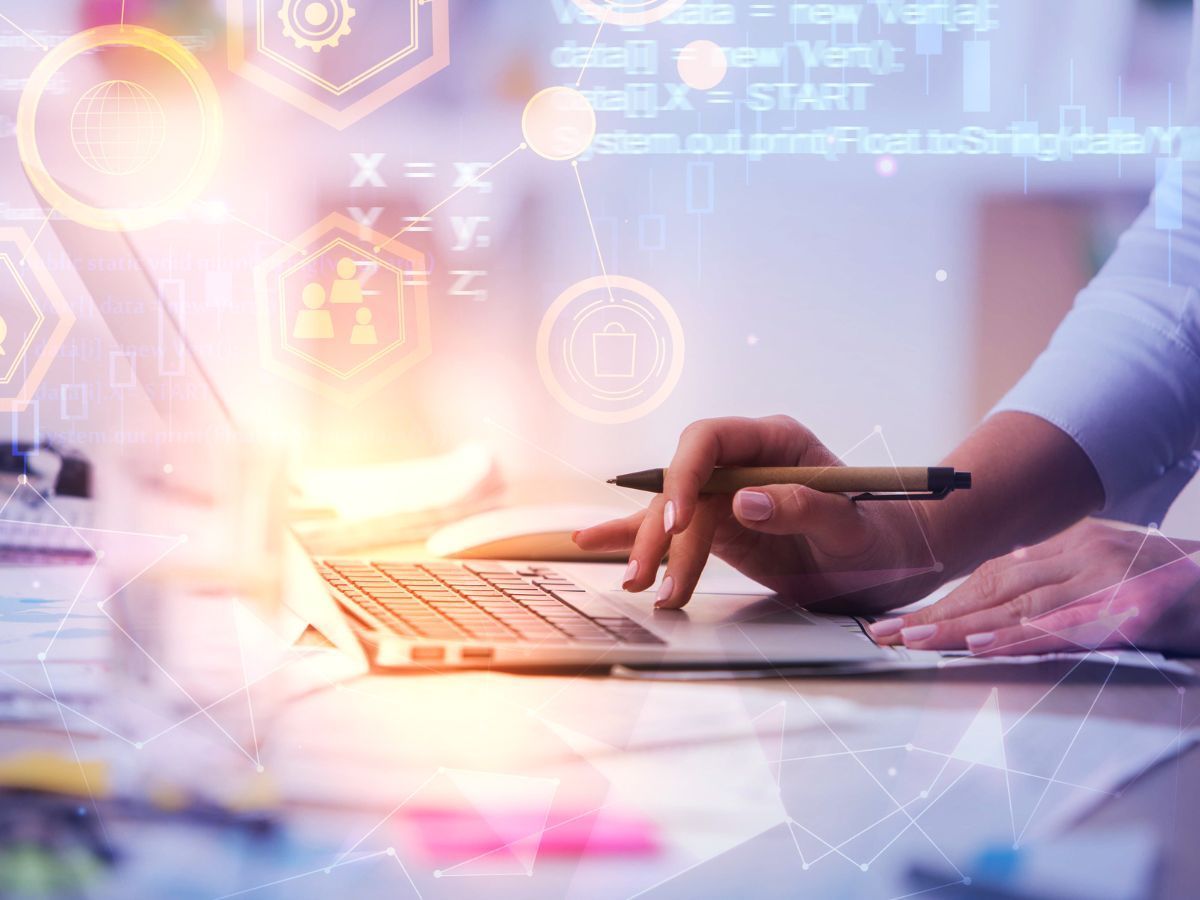 Des mains manipulent un ordinateur portable avec du code numérique et des graphismes superposés.
