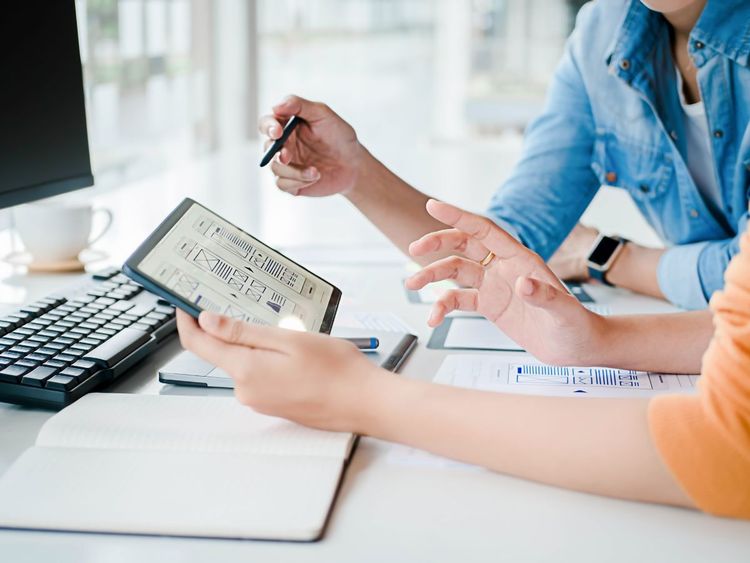 Bureau avec ordinateur, lampe, plantes et appareil photo près d'une fenêtre.