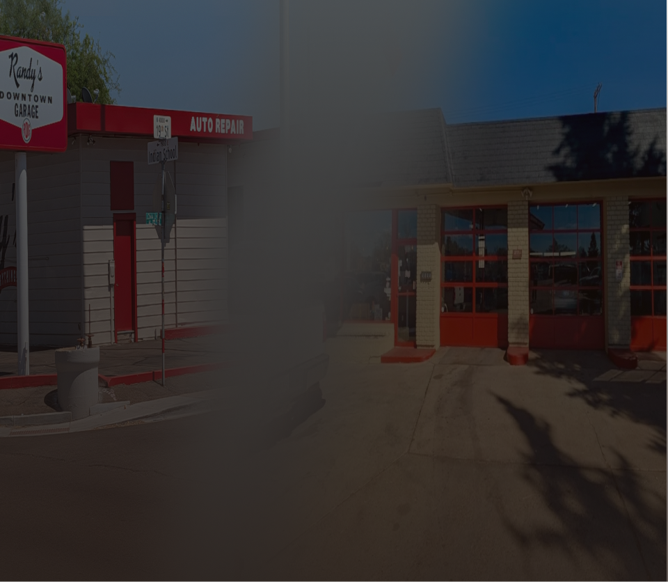 A person with a beard is working under a car in a garage | Randy's Downtown Garage