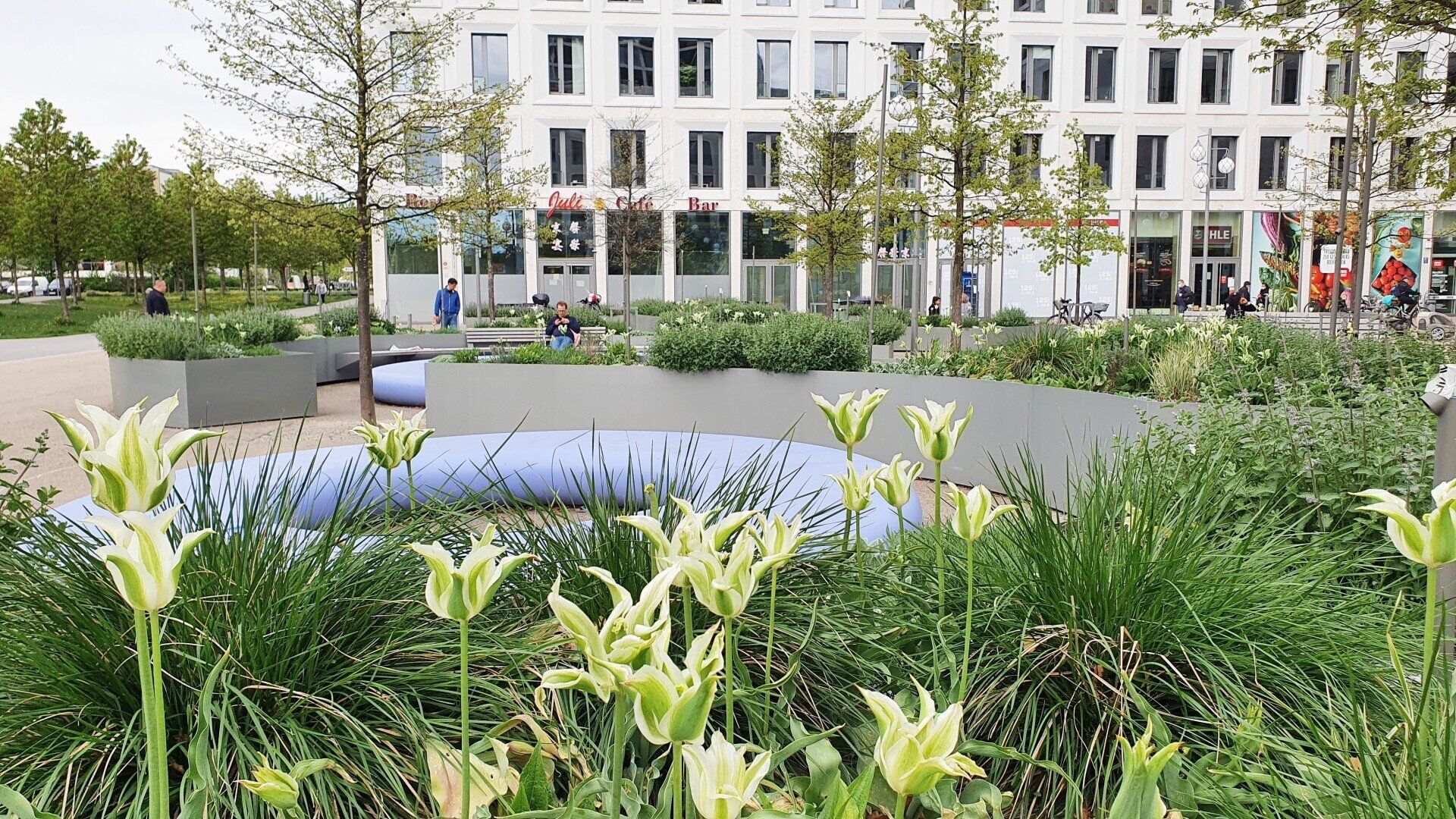 A park with flowers and trees in front of a building.